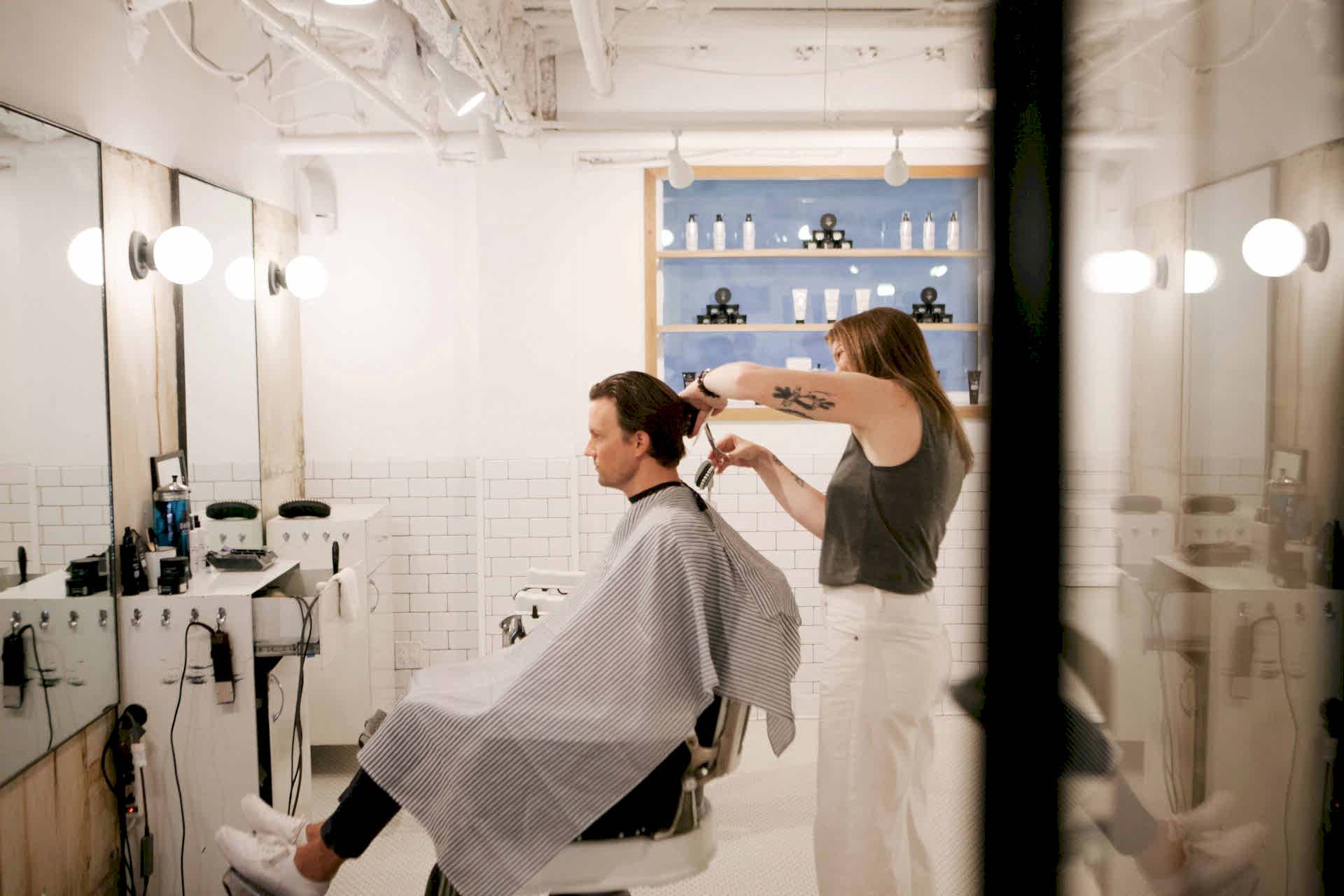man getting his hair cut by barber at blind barber moxy times square